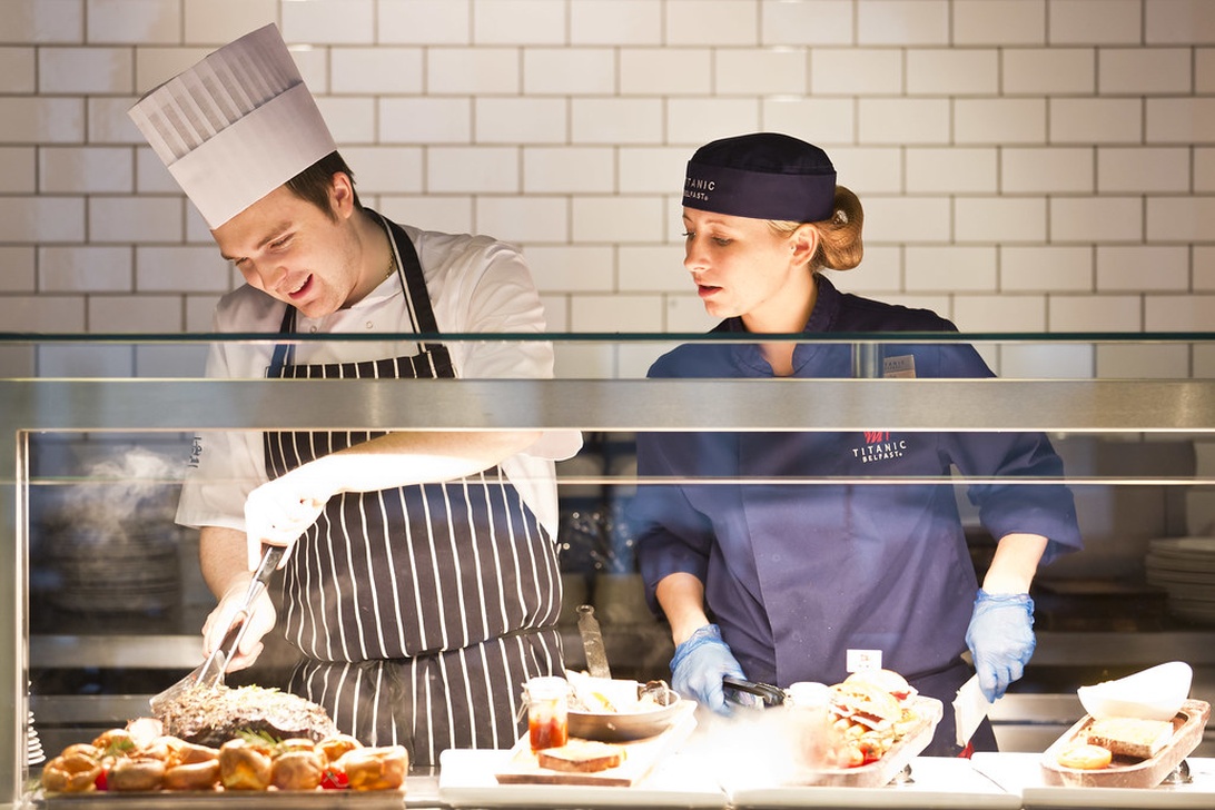 Zwei Mitarbeiter in einer professionellen Restaurantküche bereiten Speisen vor.